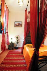 een slaapkamer met een bed met rode gordijnen bij Riad Al Mamoune in Marrakesh