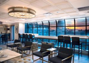 a restaurant with a bar and chairs and windows at The Madison Concourse Hotel in Madison