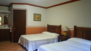 ein Schlafzimmer mit zwei Betten und einem Tisch mit Lampe in der Unterkunft Hotel Posada San Jerónimo in Coatepec