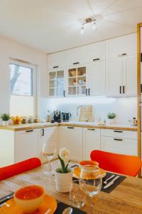 グダニスクにあるWektor Idea Apartment Gdańskのキッチン(白いキャビネット、テーブル、オレンジの椅子付)