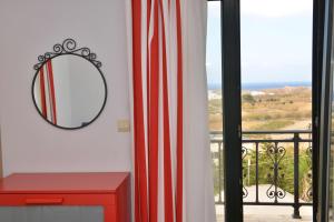 un espejo en una pared junto a un tocador rojo en Paradisia Villas, en Naxos Chora