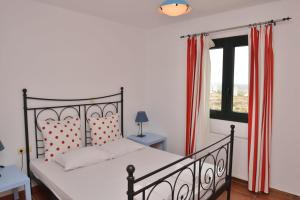 a bedroom with a bed with red curtains and a window at Paradisia Villas in Naxos Chora