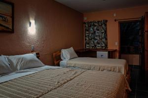 a hotel room with two beds and a window at Hotel Alta Vista in Canoa Quebrada