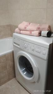 Comfortable apartments في روفنو: غسالة ملابس عليها منشفة وردية