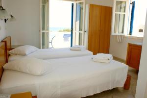 two beds in a room with a large window at Blue Bay Villas in Kamari