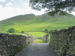 a stone wall with a gate and a mountain at The Wayside and Whisky Barn in Whitbeck