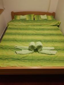 a bed with green sheets with two towels on it at Apartments REST - Bulevar in Novi Sad