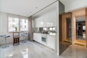 ウィーンにあるElegant Cozy Apartmentの白いキャビネットとテーブルと椅子のあるキッチン