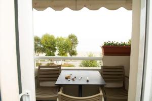 a table and chairs on a balcony with a window at Giorgos Apartments Sea View in Olympiaki Akti