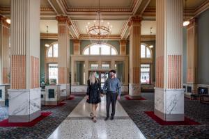 Um homem e uma mulher a andar por um corredor num edifício. em Finlen Hotel and Motor Inn em Butte