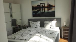 - une chambre dotée d'un lit avec des draps blancs et une photo dans l'établissement Ferienwohnung Romeike "NewPort", à Bremerhaven