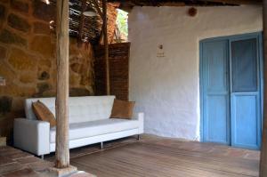 a white couch sitting on a porch with a blue door at Casa Taller in Barichara
