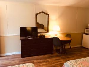 a bedroom with a dresser with a television and a table at Tumbleweed Motel in Cache Creek
