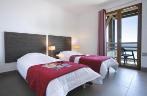 a hotel room with two beds and a balcony at Résidence Le Pic de l'Ours in Font-Romeu