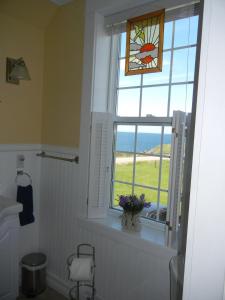 a bathroom with a window with a view of the ocean at The Yellow Sidecar B&B in Cap Le Moine