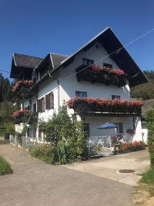 a white house with flower boxes and an umbrella at Villa Nusswald in Krumpendorf am Wörthersee