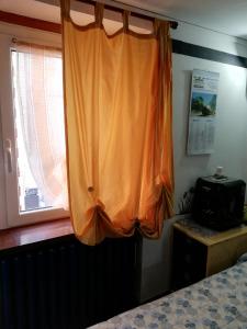 モンドヴィにあるLa casa di Adriのベッドルーム1室(窓、オレンジ色のカーテン付)