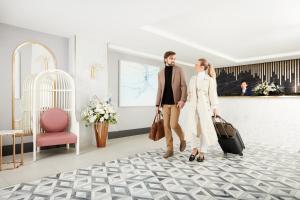 a man and woman walking through a room with luggage at EXchange Hotel Vancouver in Vancouver