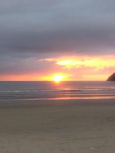 una puesta de sol en una playa con el océano en Pousada Itália, en Guarujá