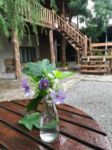 un jarrón lleno de flores púrpuras sentado en una mesa de madera en Petit Paramata, en Phitsanulok