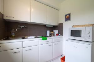 eine Küche mit weißen Schränken und einer Mikrowelle in der Unterkunft Big 1 Room Apartment - 15 Min Messe DUS in Meerbusch