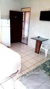 Zimmer mit einem Tisch, einem Tisch und einem Kühlschrank in der Unterkunft Pousada Lunar in Parnaíba