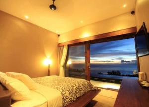 a bedroom with a bed and a large window at The Puncak Lombok in Senggigi