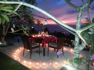 a table with candles and lights on a deck at night at The Puncak Lombok in Senggigi