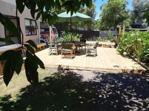 un patio con mesa, sillas y sombrilla en Murrays On Mary en Whangamata