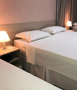 two beds in a hotel room with a lamp on a table at Hotel San Remo in Jequié