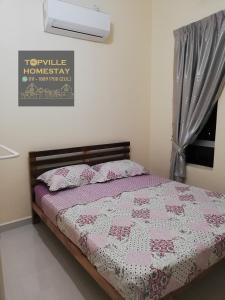 a bedroom with a bed with a pink and white quilt at Topville Homestay in Kangar