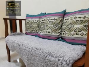 un banco con almohadas en una habitación en Topville Homestay, en Kangar