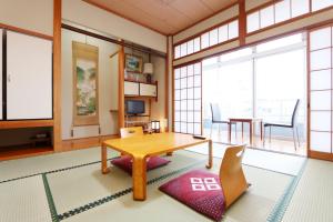 een woonkamer met een tafel, stoelen en ramen bij Ebisusou in Takashima