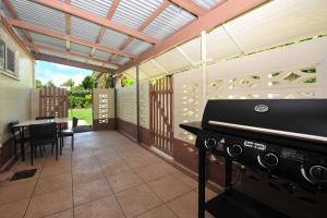 a patio with a grill and a table with chairs at Seascape Holidays - 53 Reef Street in Port Douglas