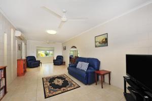 a living room with blue chairs and a flat screen tv at Seascape Holidays - 53 Reef Street in Port Douglas