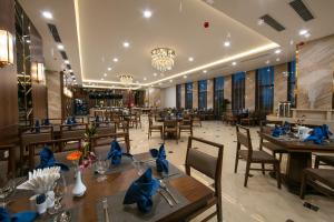 a restaurant with wooden tables and chairs and a chandelier at Ha Long Marina Hotel in Ha Long