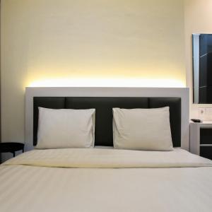 a bedroom with a bed with white pillows at 1BR Brooklyn Alam Sutera Apartment near BINUS By Travelio in Dongkal Dua