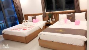 two beds in a room with pink decorations on them at Trang Ngan Hotel by THG in Danang