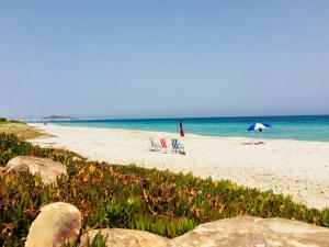 duas cadeiras e um guarda-sol numa praia em Casa del Mar Residence em Kelibia