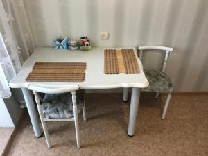 a table with two chairs and a white table with two mats at Apartment on Amurskiy Bulvar 62 in Khabarovsk