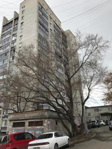 two cars parked in front of a tall building at Apartment on Amurskiy Bulvar 62 in Khabarovsk