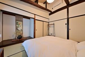 a bedroom with a white bed and windows at Luxury Machiya Takeya Nishijin in Kyoto