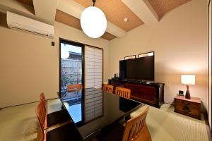 a living room with a television and a table and chairs at Luxury Machiya Takeya Nishijin in Kyoto