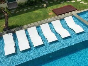 a row of white chairs sitting on top of a swimming pool at Anja Jimbaran in Jimbaran