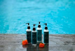 a group of four bottles sitting next to a pool at Anja Jimbaran in Jimbaran