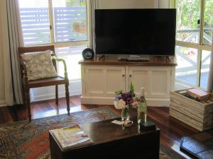uma sala de estar com uma televisão de ecrã plano num centro de entretenimento em Kidd Street Cottages em Mount Tamborine