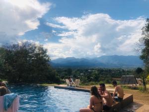 a group of people sitting around a swimming pool at Pai circus hostel in Pai