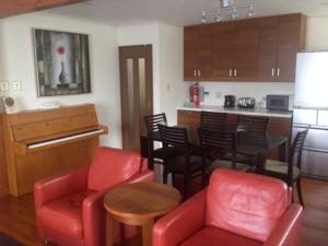 a living room with red chairs and a kitchen at Happo One Holiday House in Hakuba