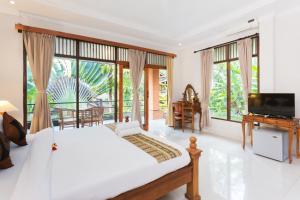 a bedroom with a bed and a tv and windows at Rahayu Suites Monkey Forest Ubud in Ubud