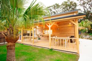 a wooden cabin in a garden with a palm tree at Tabist Pumping Surf in Hyuga